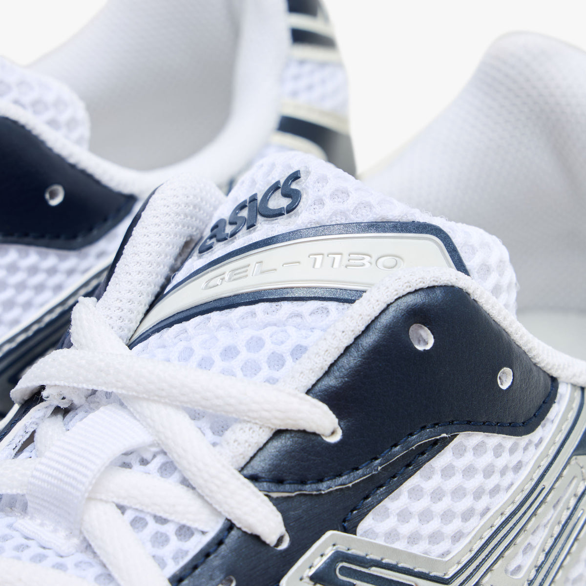 ASICS GEL-1130. Close-up view of the throat and collar region highlighting white open mesh, dark midnight blue synthetic eyestays, white laces, and tongue badge with ASICS GEL-1130 branding.