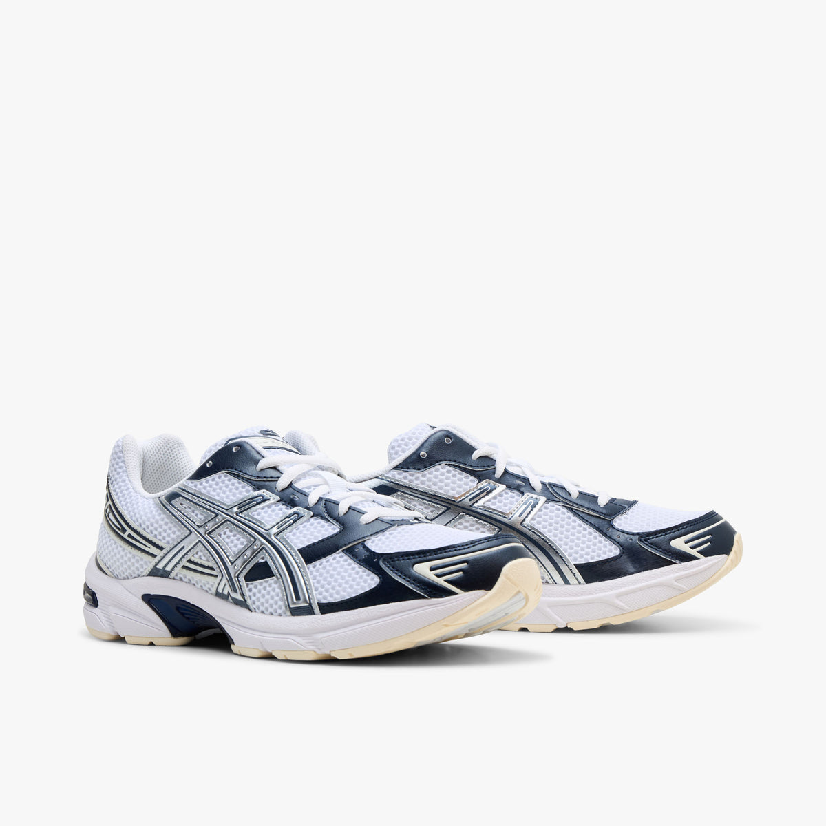 ASICS GEL-1130. Three-quarter view of a pair of running sneakers displaying white mesh uppers, dark midnight blue synthetic overlays, metallic silver Tiger Stripes, white laces, and off-white cushioned midsoles.