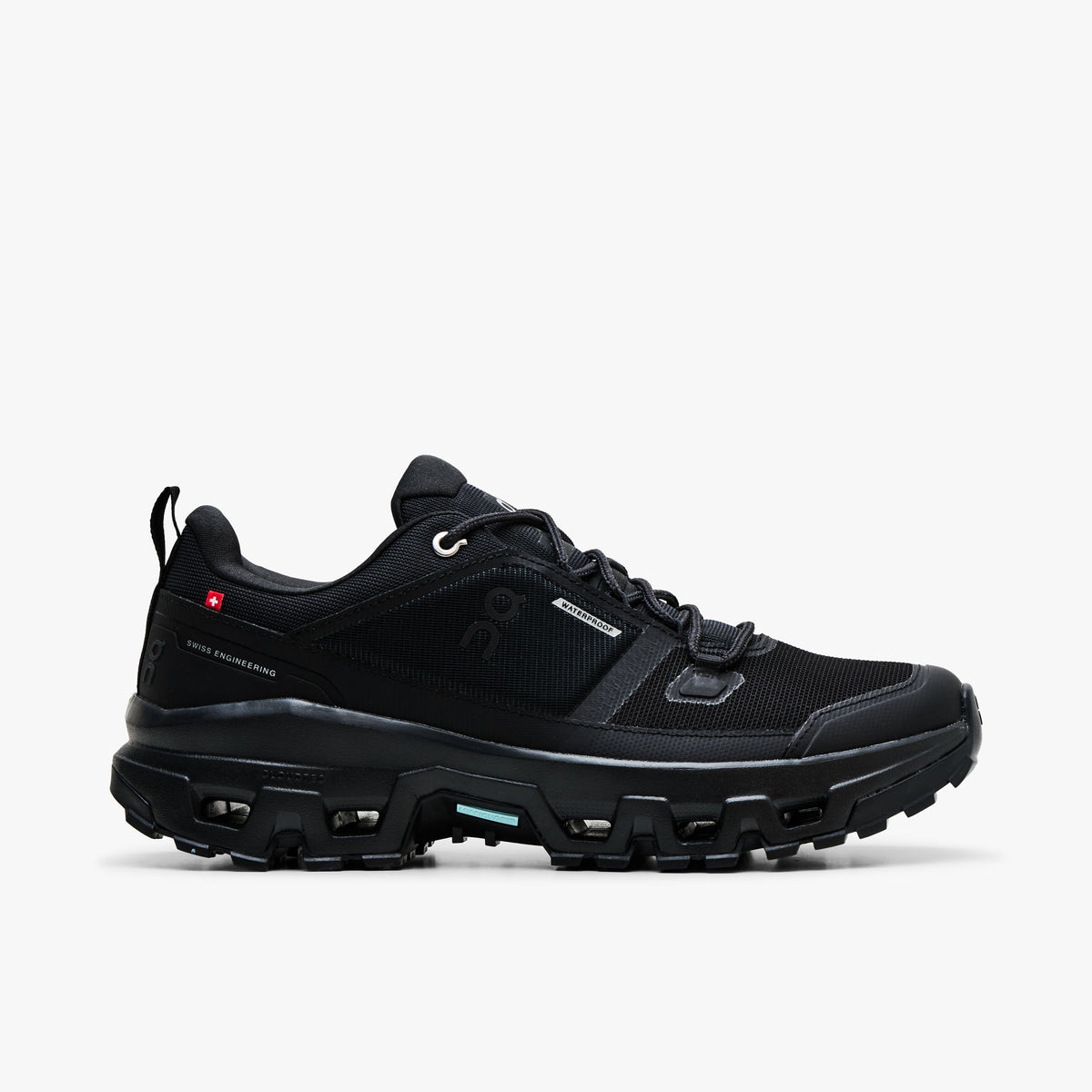 On Cloudrock Low Waterproof. Profile view featuring all-black waterproof membrane upper, protective TPU mudguard, tonal On branding, and CloudTec lugged trail midsole.