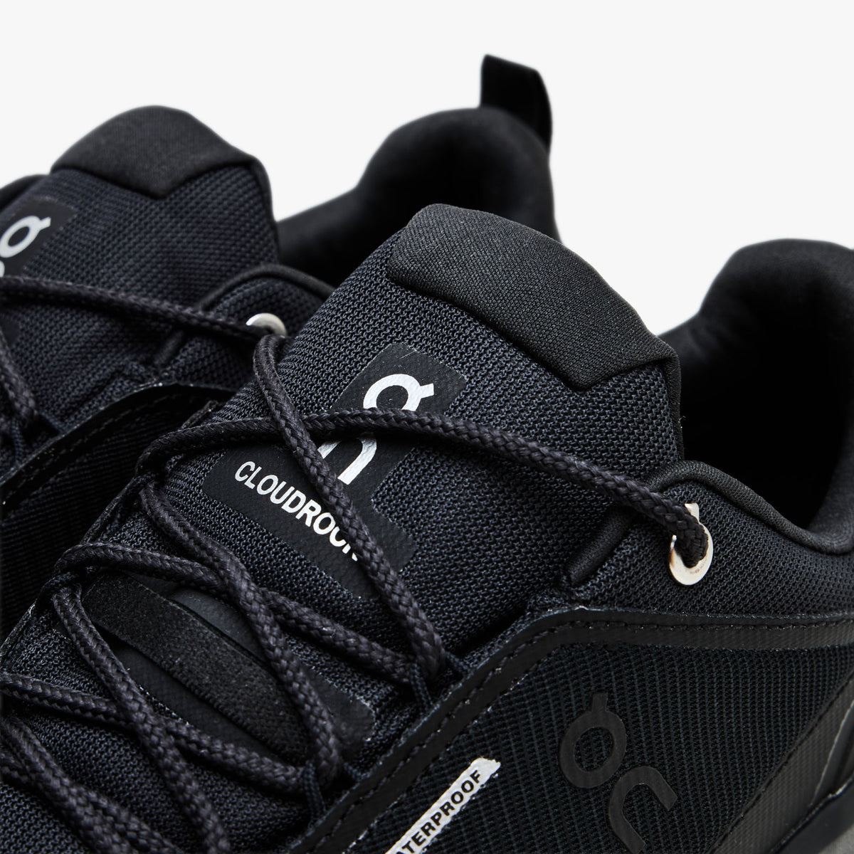 On Cloudrock Low Waterproof. Close-up view showcasing black lacing system, metallic top eyelets, tongue pull tab, and silver On logo branding.