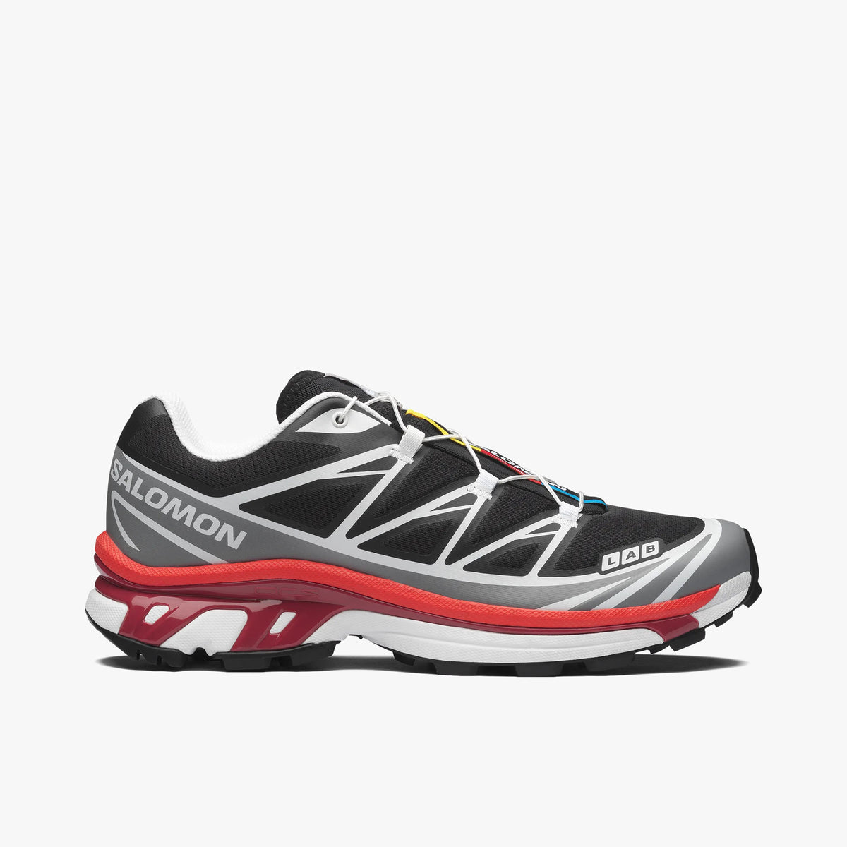 Salomon XT-6. Side view of technical trail running sneakers featuring a black abrasion-resistant mesh upper, alloy grey welded Sensifit TPU film overlays, white contrast piping, LAB branding on the forefoot, white Salomon text on the rear quarter, lava falls red Agile Chassis System stability rim, dual-density midsole, and a black lugged Contagrip outsole.