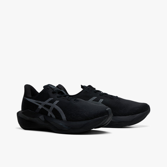 ASICS NOVABLAST 6. Three-quarter view of black running shoes with black laces, grey ASICS stripes and curved midsoles.
