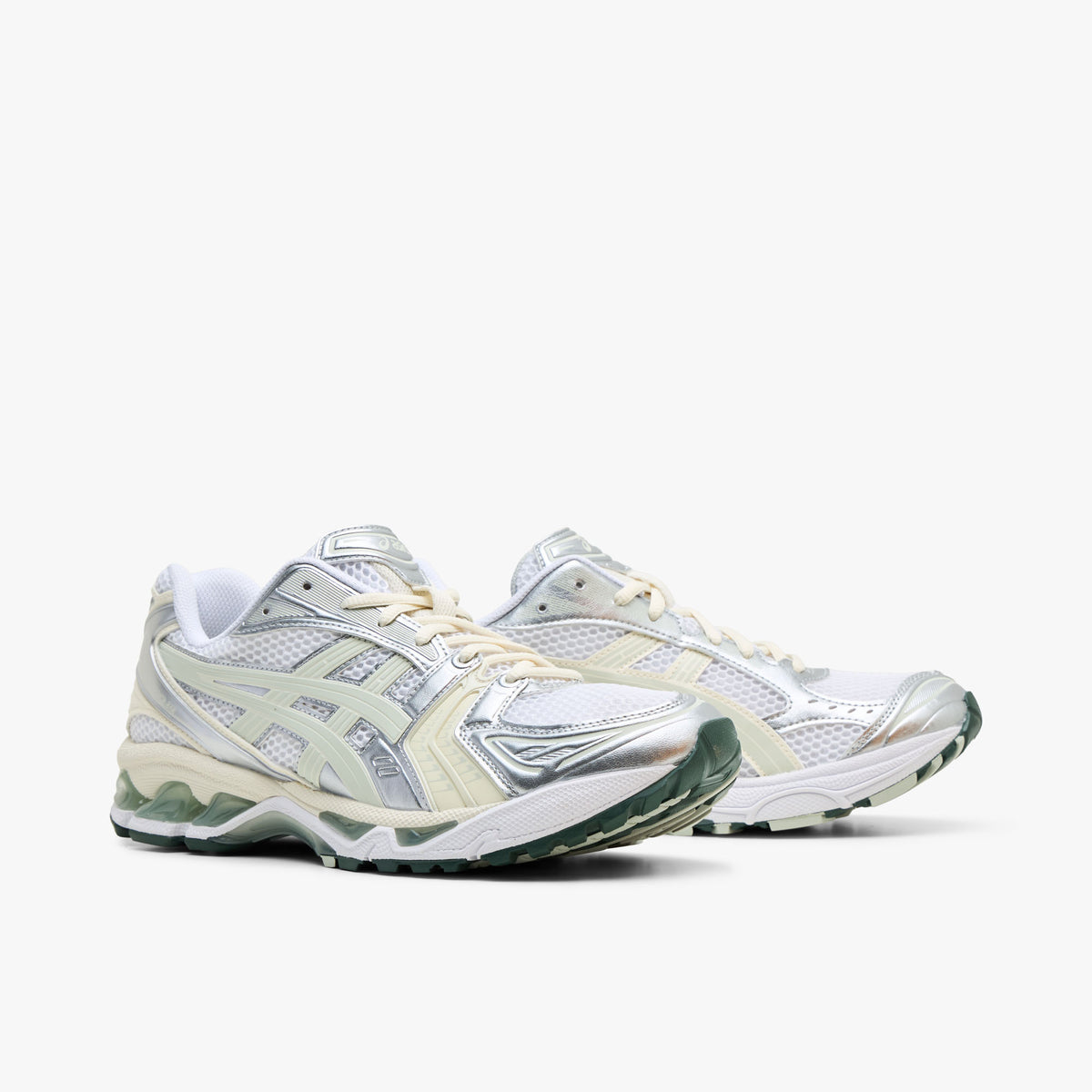 ASICS GEL-KAYANO 14. Three-quarter view of a pair of running sneakers displaying white mesh uppers, metallic silver and light sage overlays, cream laces, and white midsoles with green GEL cushioning inserts. 