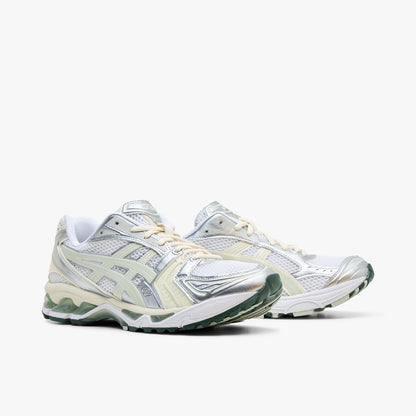 ASICS GEL-KAYANO 14. Three-quarter view of a pair of running sneakers displaying white mesh uppers, metallic silver and light sage overlays, cream laces, and white midsoles with green GEL cushioning inserts. 
