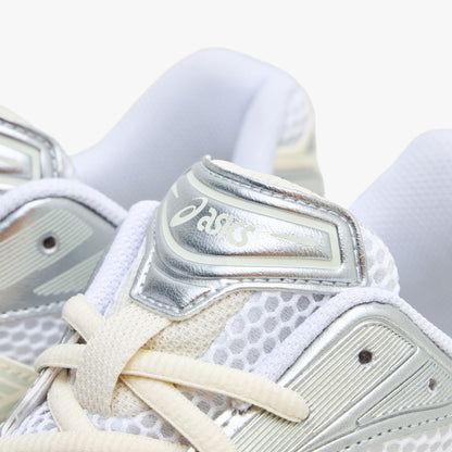ASICS GEL-KAYANO 14. Close-up view of the tongue and collar region highlighting white open mesh, light sage eyestays, cream laces, and a metallic silver tongue badge with ASICS branding. 