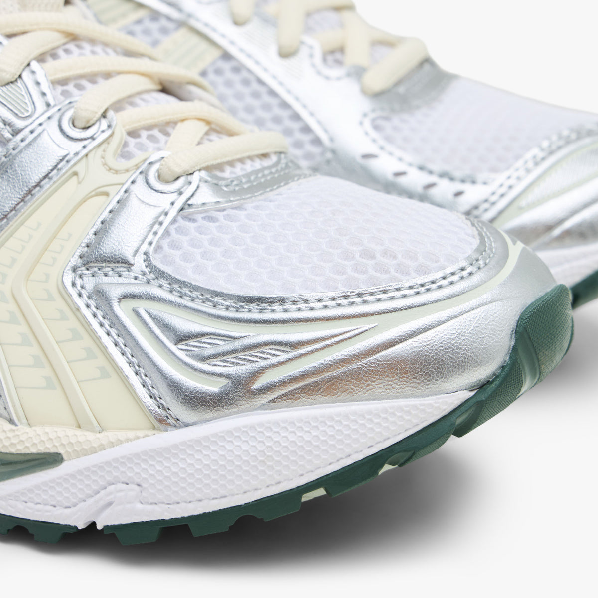 ASICS GEL-KAYANO 14. Close-up view of the forefoot showing a white mesh toe box, metallic silver and light sage synthetic overlays, white midsole, and dark sage green outsole tip. 
