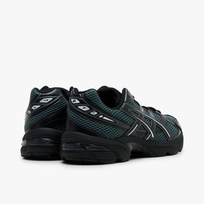 ASICS GEL-1130. Rear three-quarter view showing black synthetic heel overlays with silver line accents, dusty fern mesh collars, and black GEL-cushioned midsoles. 