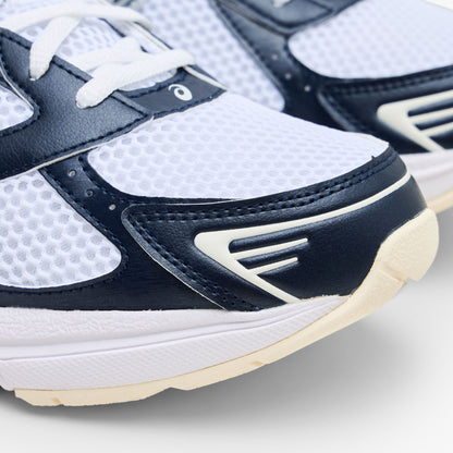 ASICS GEL-1130. Close-up view of the forefoot showing white mesh toe box, dark midnight blue synthetic mudguard overlay, off-white midsole rim, and geometric toe accents. 