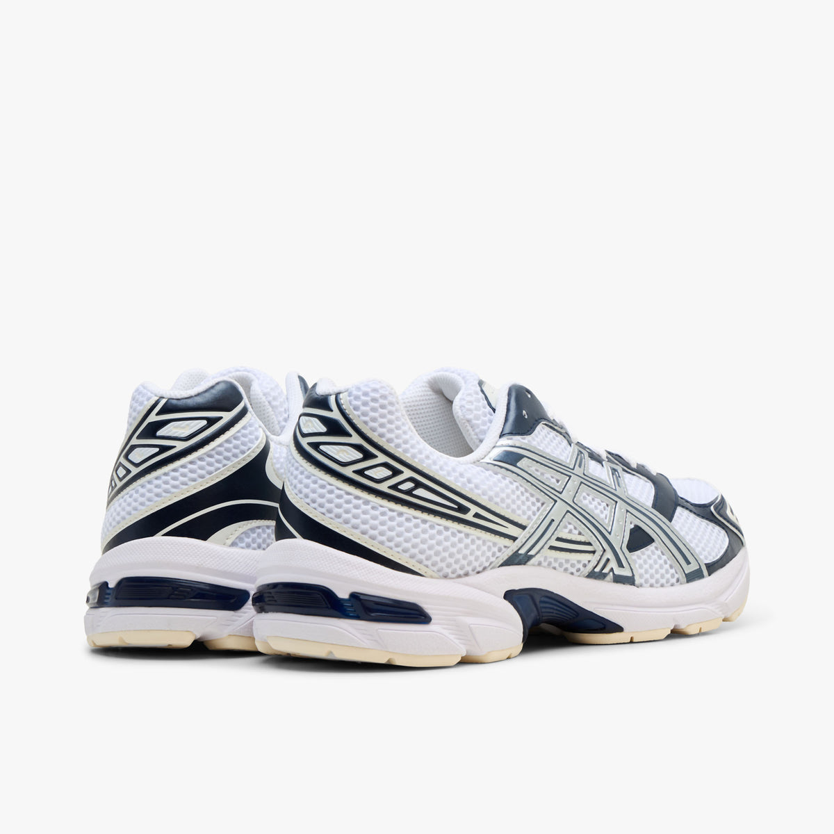 ASICS GEL-1130. Rear three-quarter view showing white mesh heel collars, dark midnight blue synthetic heel overlays with silver accents, and off-white GEL-cushioned midsoles. 