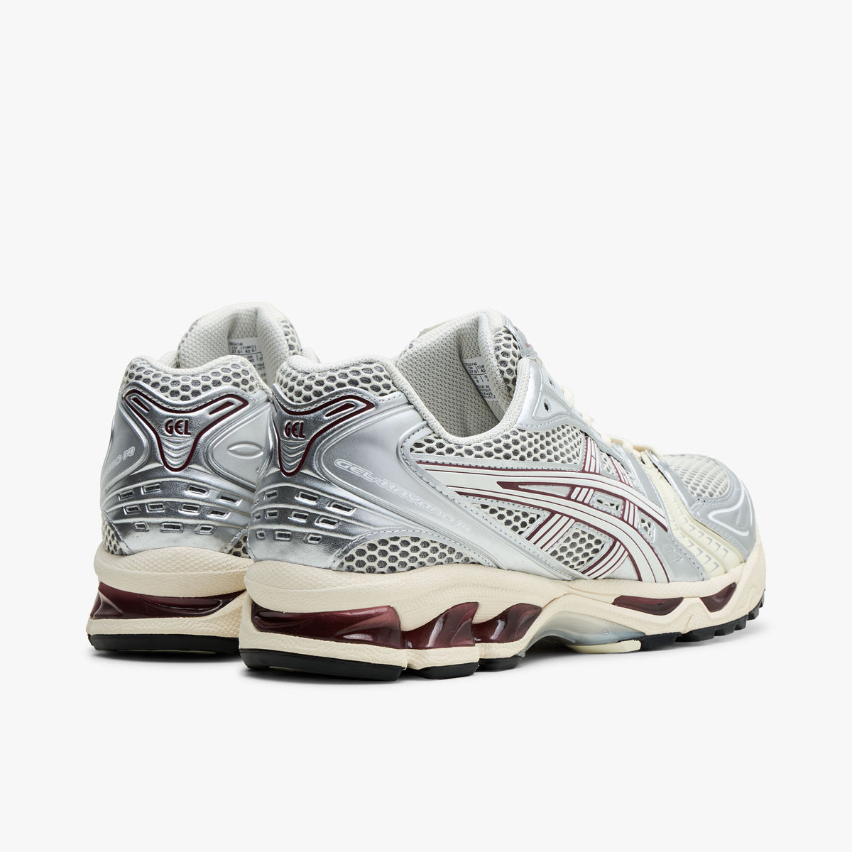 ASICS GEL-KAYANO 14. Rear view of silver and Cream running shoes showing metallic heel overlays and dark red GEL cushioning inserts. 