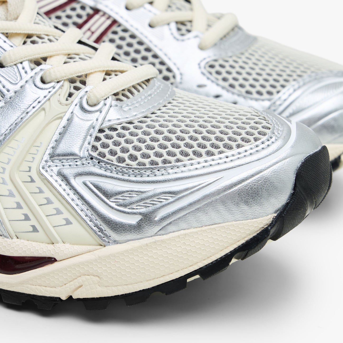 ASICS GEL-KAYANO 14. Close-up of metallic silver synthetic overlays, open mesh toe box, and cream rubber midsole tip. 