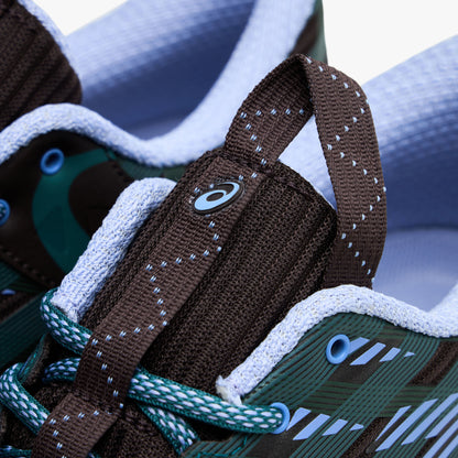 Asics US8-S GEL-SJ33. Close-up of roasted coffee and periwinkle sneaker showing brown tongue, teal laces, blue eyelets and patterned upper.