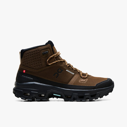On Cloudrock Mid Waterproof. Profile view featuring earth brown technical mesh upper, mid-cut ankle collar, black protective mudguard, speed-lacing hooks, and black CloudTec trail midsole. 