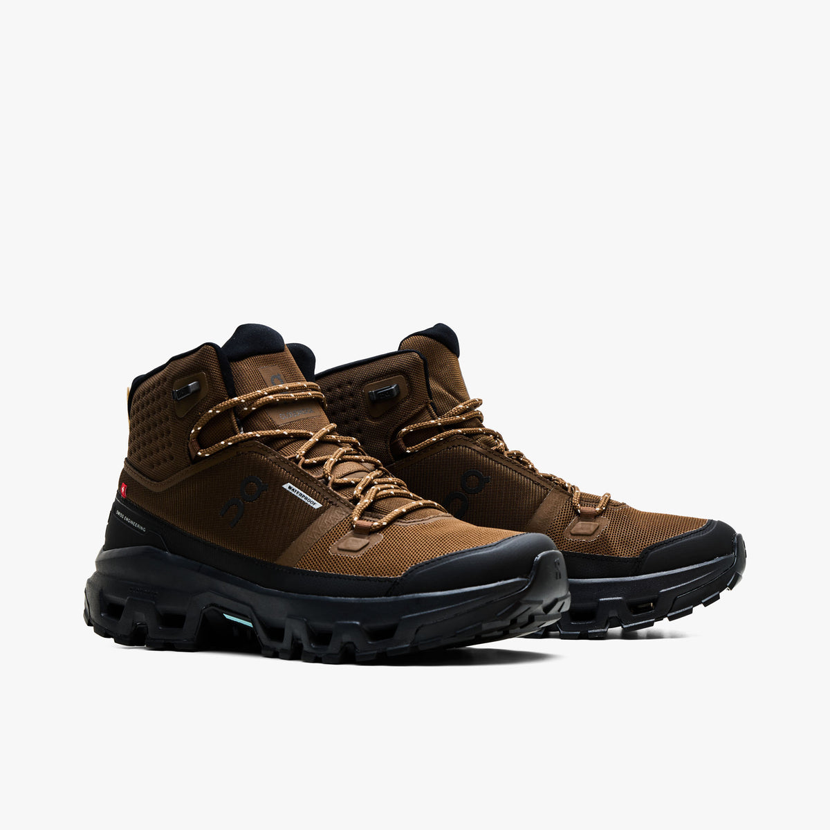 On Cloudrock Mid Waterproof. Three-quarter view of pair showcasing earth brown waterproof mesh construction, black synthetic overlays, speckled hiking laces, and rugged trail soles. 
