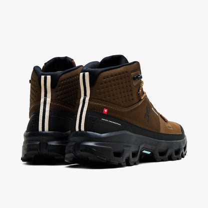 On Cloudrock Mid Waterproof. Back view displaying mid-cut earth brown ankle collar with vertical beige pull stripes, red Swiss flag detail, and black heel counter cushioning. 