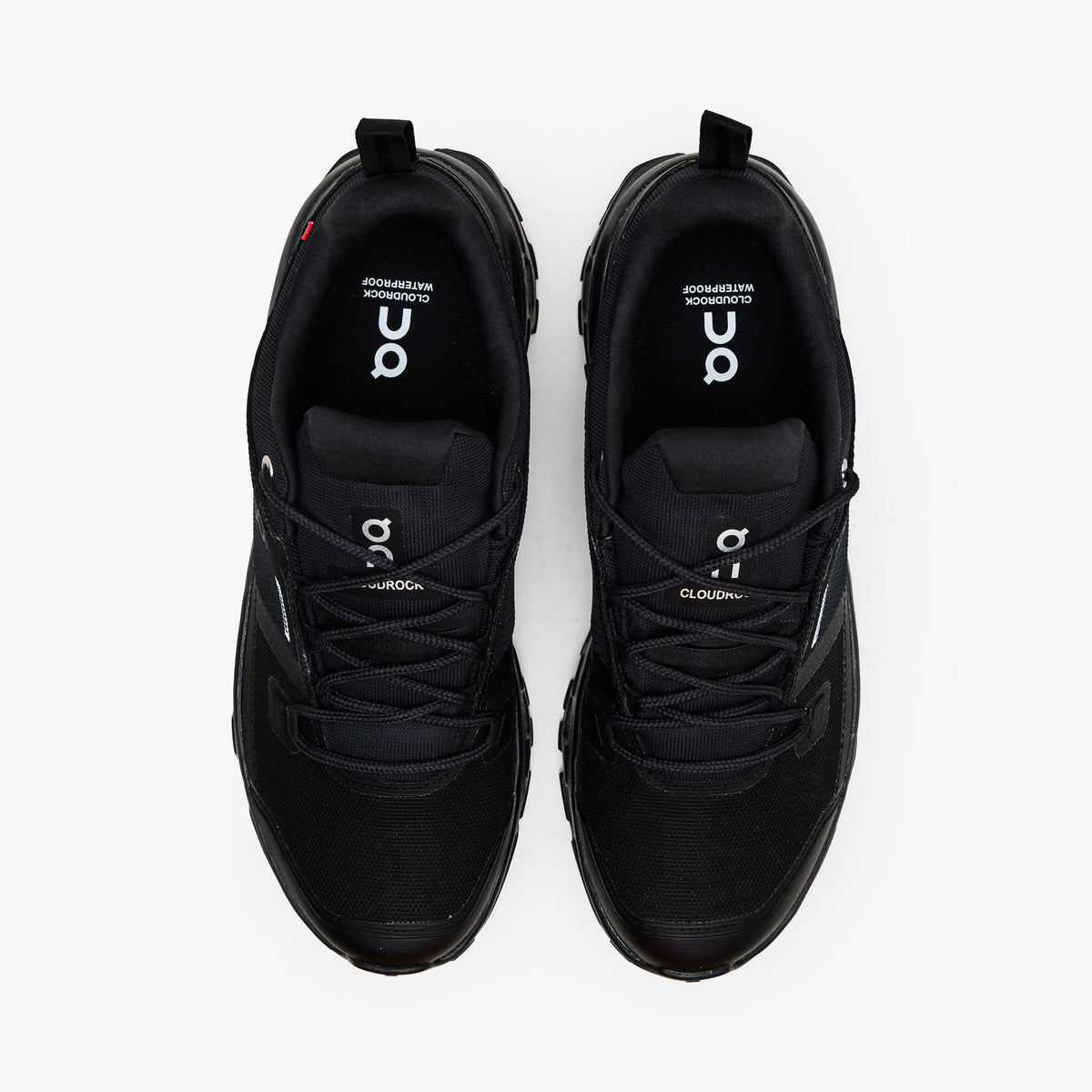 On Cloudrock Low Waterproof. Top-down view showcasing black waterproof toe boxes, technical lacing system, plush collars, and branded insoles. 