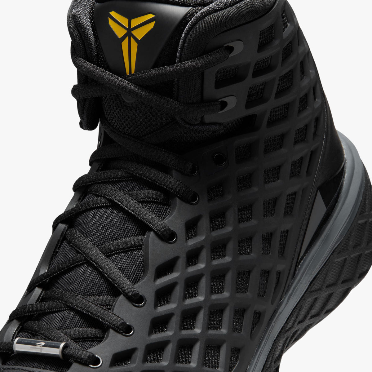 Nike Kobe III Protro. Close-up front view of upper and collar showing black diamond mesh netting, black laces, and tongue top displaying gold embroidered Kobe Sheath logo. 