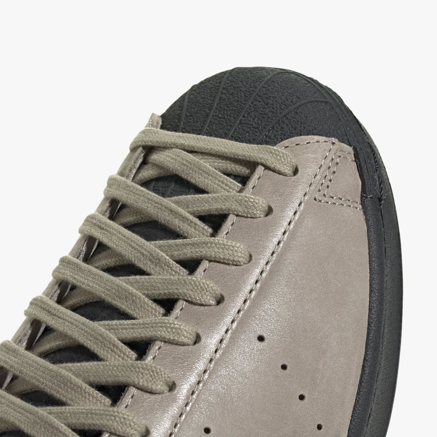 adidas Superstar Vintage Short Shell. Close-up of Carbon rubber short shell toe, beige laces, and perforated side ventilation details. 