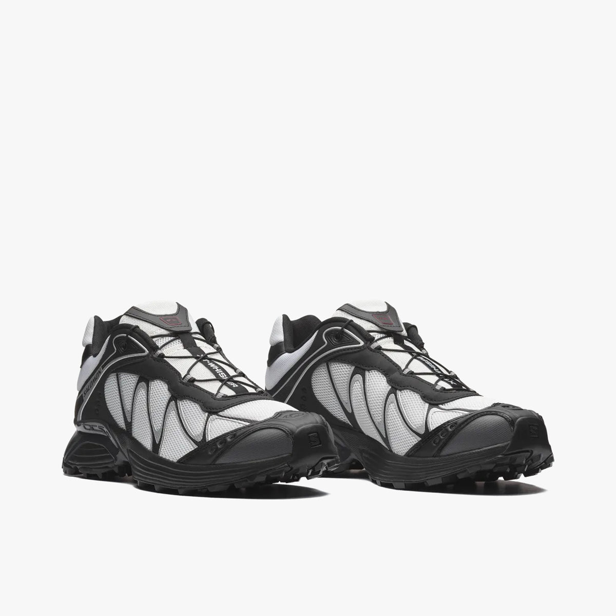 Salomon XT-WHISPER. Three-quarter view of a pair of trail running sneakers displaying white textile uppers, black TPU overlays, Quicklace speed lacing system, and black cushioned midsoles. 