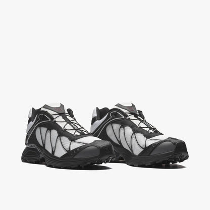 Salomon XT-WHISPER. Three-quarter view of a pair of trail running sneakers displaying white textile uppers, black TPU overlays, Quicklace speed lacing system, and black cushioned midsoles. 