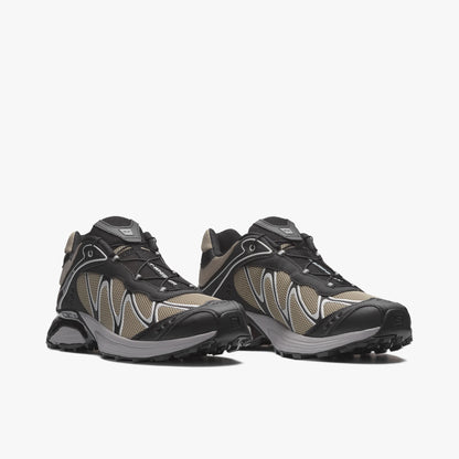 Salomon XT-WHISPER. Three-quarter view of a pair of trail running sneakers displaying silver sage mesh uppers, black TPU overlays, Quicklace speed lacing system, and dual-density cushioned midsoles. 