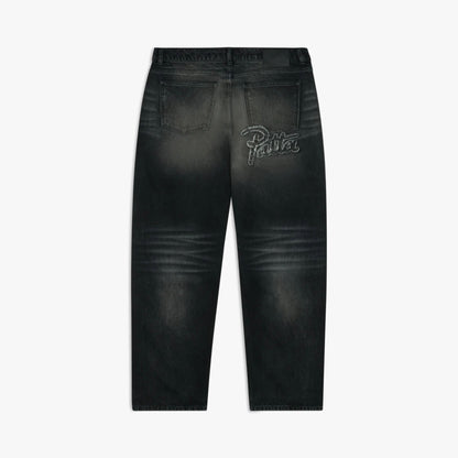 Patta Dark Dirty Whiskers Baggy Denim Pants. Flat lay back view showing the relaxed-fit black washed denim jeans, rear patch pockets with script logo embroidery on the right pocket, leather waistband patch, and wide straight-leg hemline. 