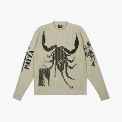 Patta Scorpio Knitted Jumper. Flat lay front view of a long-sleeve knit sweater featuring a beige crewneck knit construction, large black jacquard-woven scorpion graphic across the chest, "PATTA" text graphic on the right sleeve, intricate floral illustration on the left sleeve, ribbed collar, ribbed cuffs, and ribbed hem. 