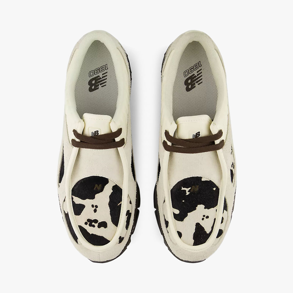 New Balance 1890A Moc-Toe. Top-down overhead view of a pair of sneakers displaying moc-toe stitched aprons with rich earth brown cow-print graphic panels, rich earth brown leather laces, and light angora insoles with New Balance logo branding. 