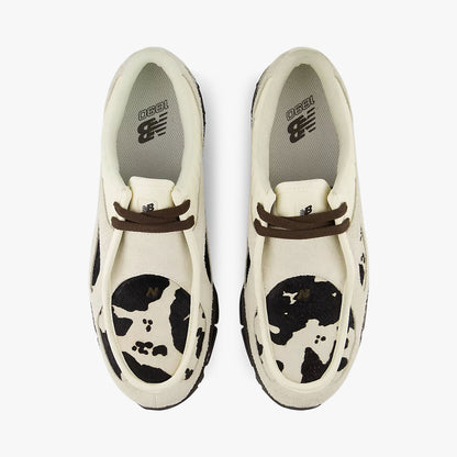 New Balance 1890A Moc-Toe. Top-down overhead view of a pair of sneakers displaying moc-toe stitched aprons with rich earth brown cow-print graphic panels, rich earth brown leather laces, and light angora insoles with New Balance logo branding. 