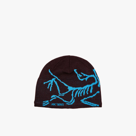 Arc'teryx Bird Head Toque. Front view featuring dark ultima purple knit construction with large bright aquaculture blue knit Archaeopteryx bird logo wrap. 