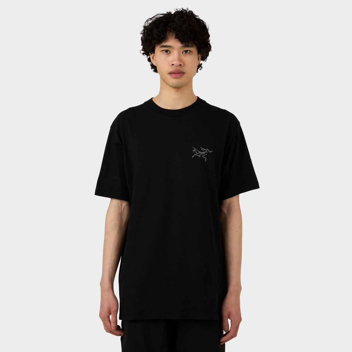 Arc'teryx Kragg SL Cotton T-Shirt. Front model view of black short-sleeve organic cotton t-shirt featuring a ribbed crewneck collar and subtle grey Arc'teryx Archaeopteryx bird logo printed on the left chest. 