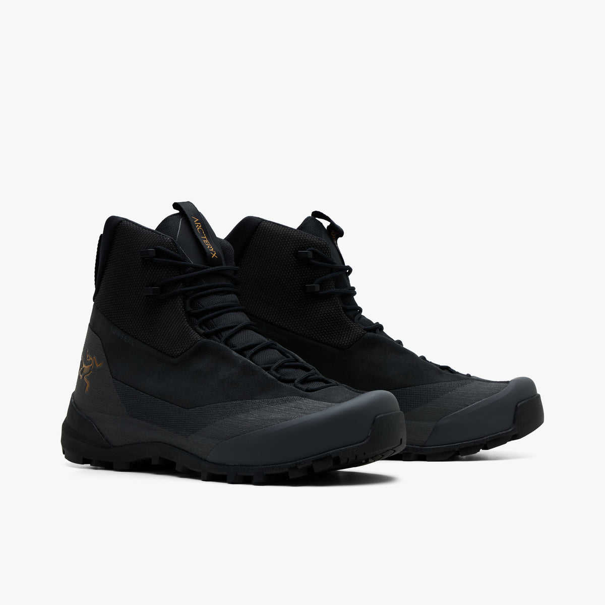 Arc'teryx Konseal Trek. Three-quarter view of a pair of mid-cut hiking boots displaying black textile and nubuck uppers, dark graphite protective rand and toe overlays, black laces, and dark trail-ready midsoles. 
