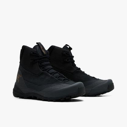 Arc'teryx Konseal Trek. Three-quarter view of a pair of mid-cut hiking boots displaying black textile and nubuck uppers, dark graphite protective rand and toe overlays, black laces, and dark trail-ready midsoles. 