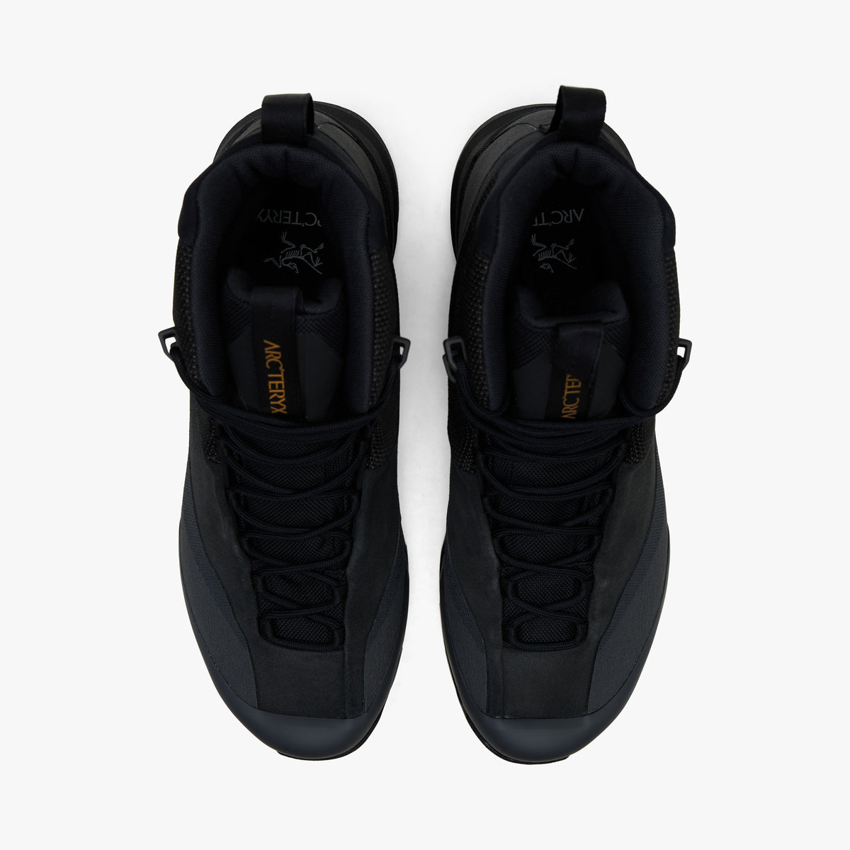 Arc'teryx Konseal Trek. Top-down overhead view of a pair of hiking boots displaying dark graphite mesh toe caps, extended climbing-style lacing, tongue pull tabs with gold branding, and black padded collar linings. 